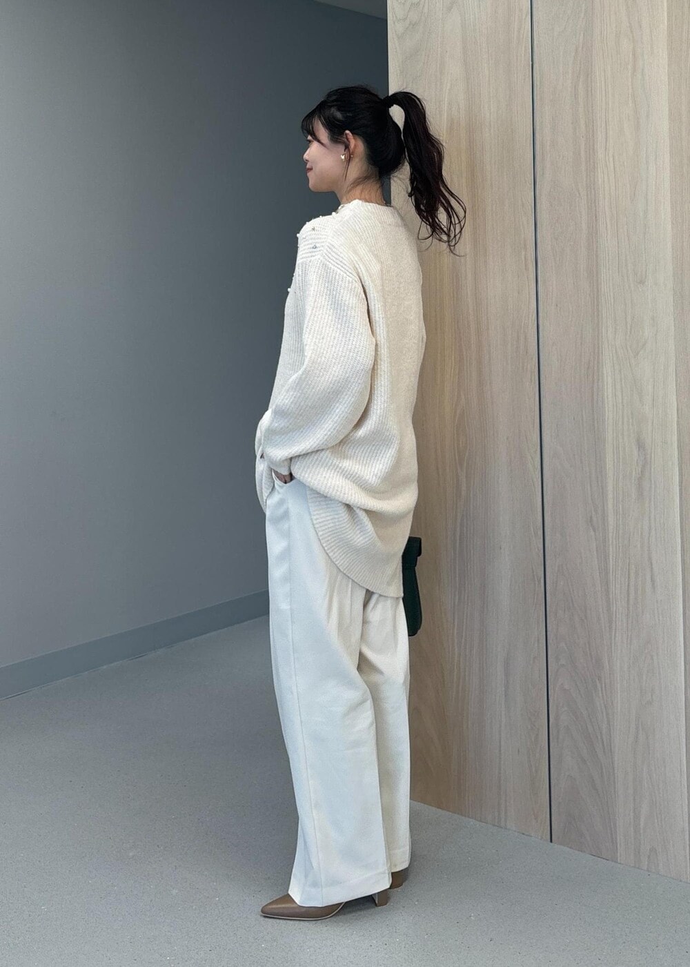 グリーン系のハンドバッグ、ベージュ系のブーツ、ホワイト系のワンピースを着用したレディースの冬コーディネートの3枚目の写真