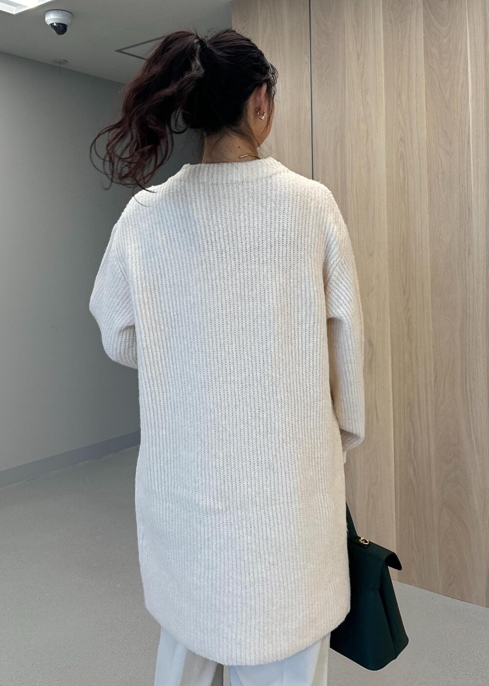 グリーン系のハンドバッグ、ベージュ系のブーツ、ホワイト系のワンピースを着用したレディースの冬コーディネートの6枚目の写真