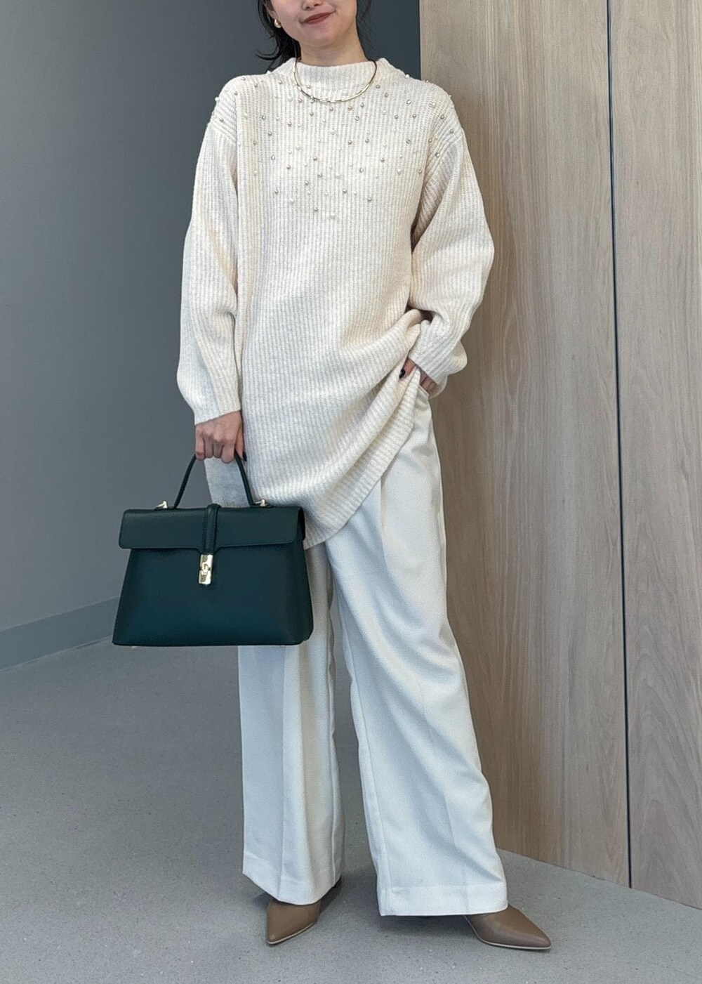 グリーン系のハンドバッグ、ベージュ系のブーツ、ホワイト系のワンピースを着用したレディースの冬コーディネートの2枚目の写真