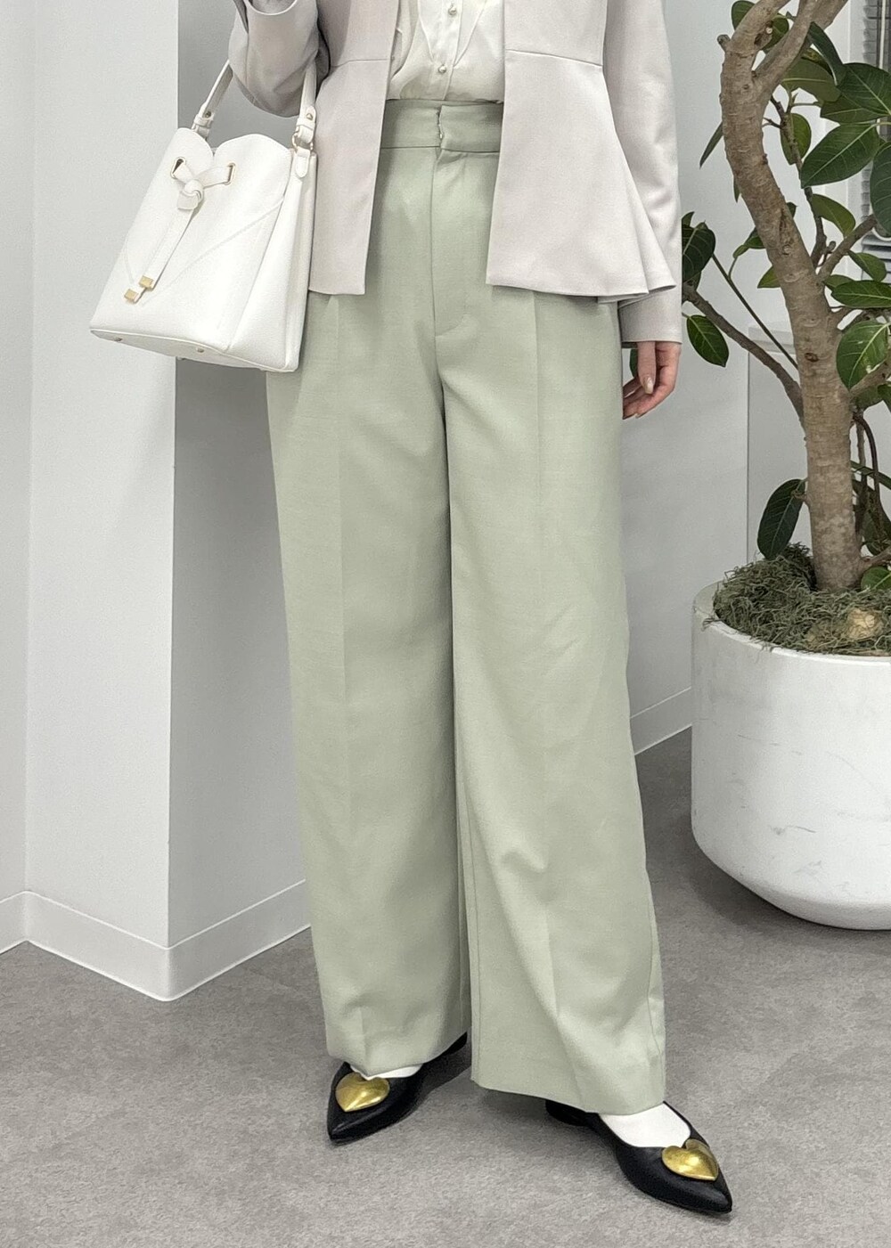 ホワイト系のショルダーバッグ、グリーン系のスラックス、ブラック系のバレエシューズを着用したレディースの冬コーディネートの5枚目の写真