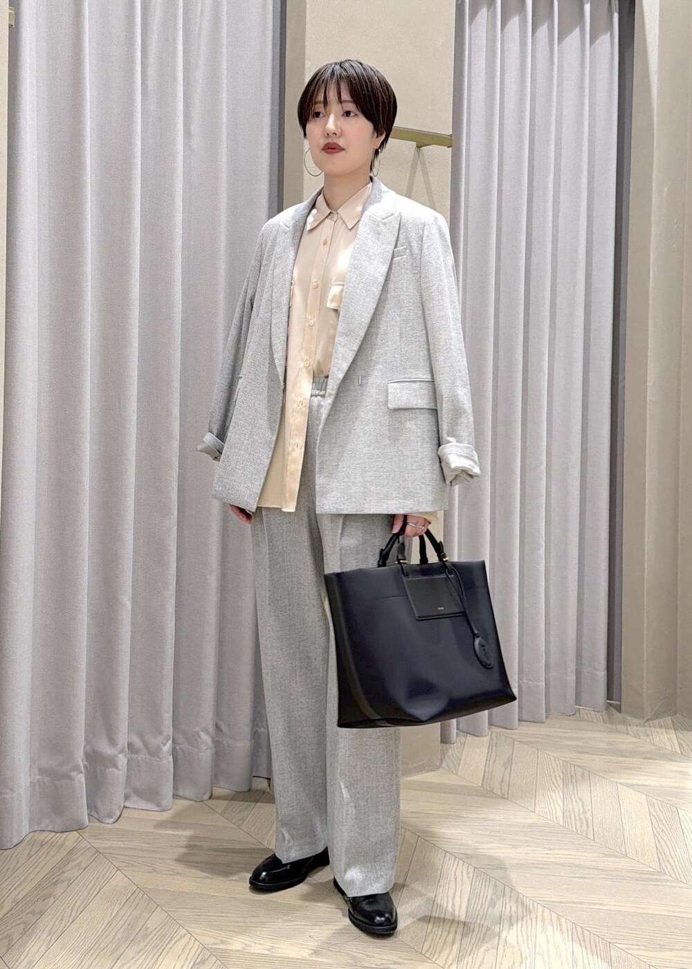 ブラック系のドレスシューズ、ブラック系のトートバッグ、グレー系のテーラードジャケットを着用したレディースの秋コーディネートの2枚目の写真