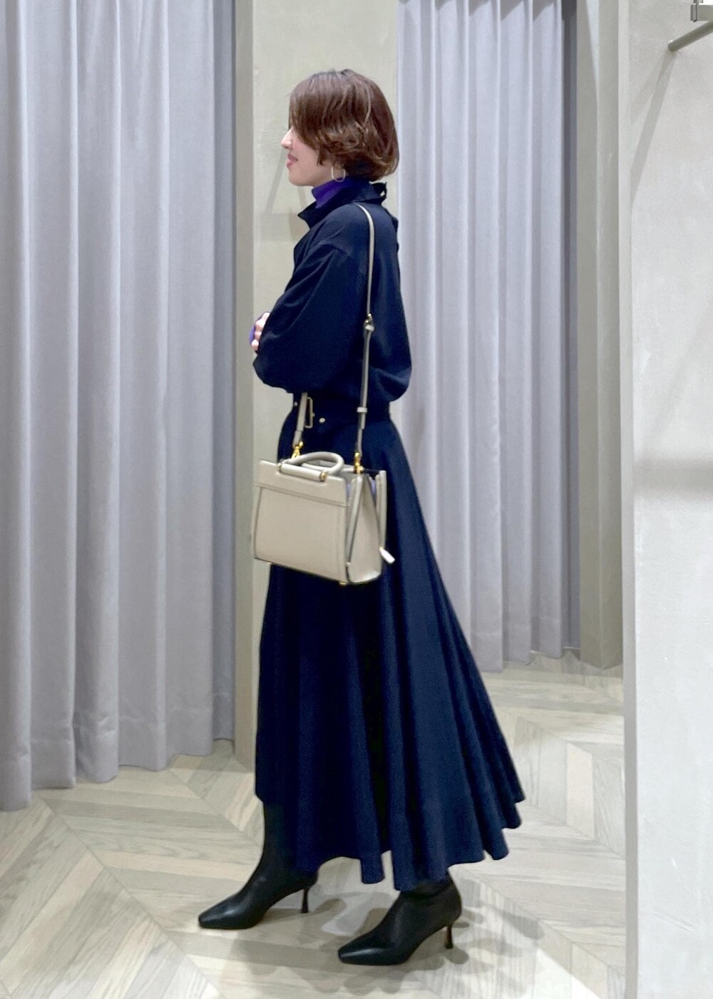 ブラック系のブーツ、ベージュ系のハンドバッグ、ブルー系のスカートを着用したレディースの冬コーディネートの2枚目の写真