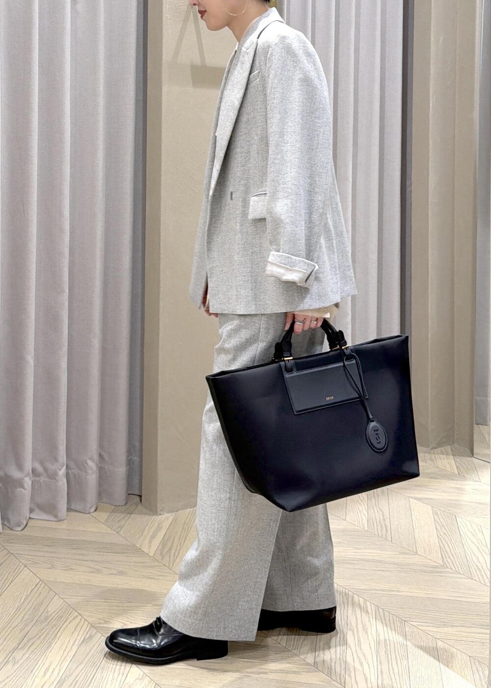 ブラック系のドレスシューズ、ブラック系のトートバッグ、グレー系のテーラードジャケットを着用したレディースの秋コーディネートの3枚目の写真