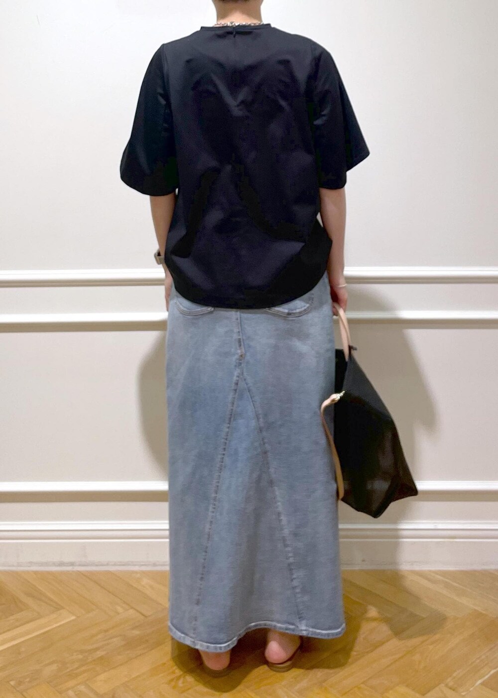 ブラック系のトートバッグ、ベージュ系のサンダル、ブラック系のTシャツ/カットソーを着用したレディースの夏コーディネートの3枚目の写真