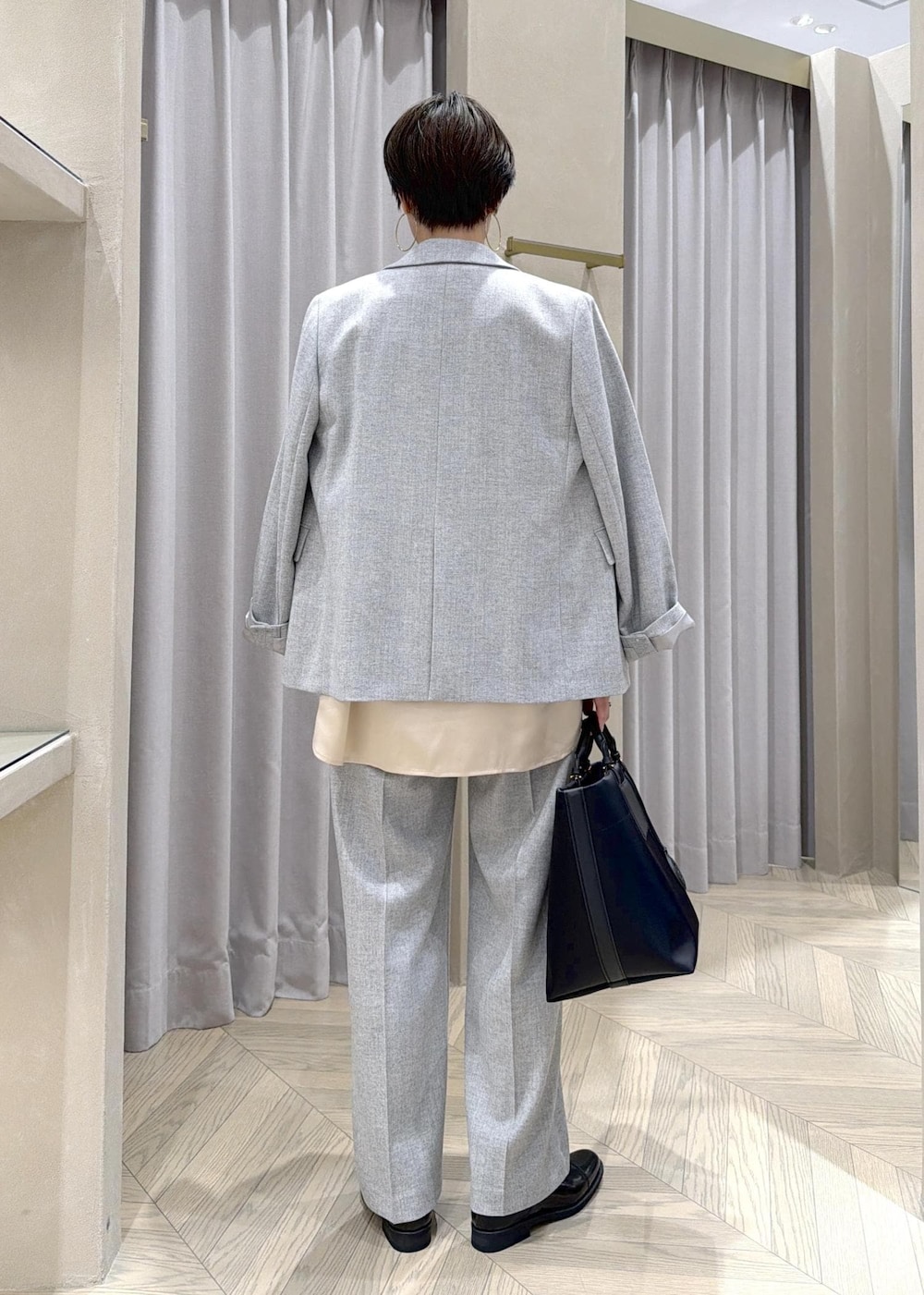 ブラック系のドレスシューズ、ブラック系のトートバッグ、グレー系のテーラードジャケットを着用したレディースの秋コーディネートの4枚目の写真