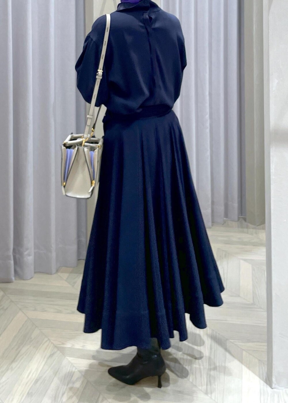 ブラック系のブーツ、ベージュ系のハンドバッグ、ブルー系のスカートを着用したレディースの冬コーディネートの4枚目の写真