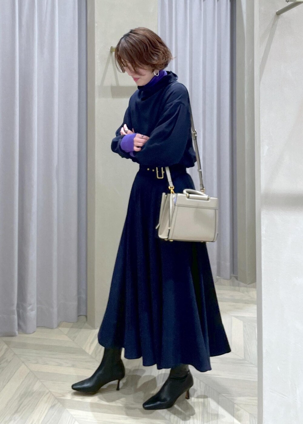 ブラック系のブーツ、ベージュ系のハンドバッグ、ブルー系のスカートを着用したレディースの冬コーディネートの3枚目の写真