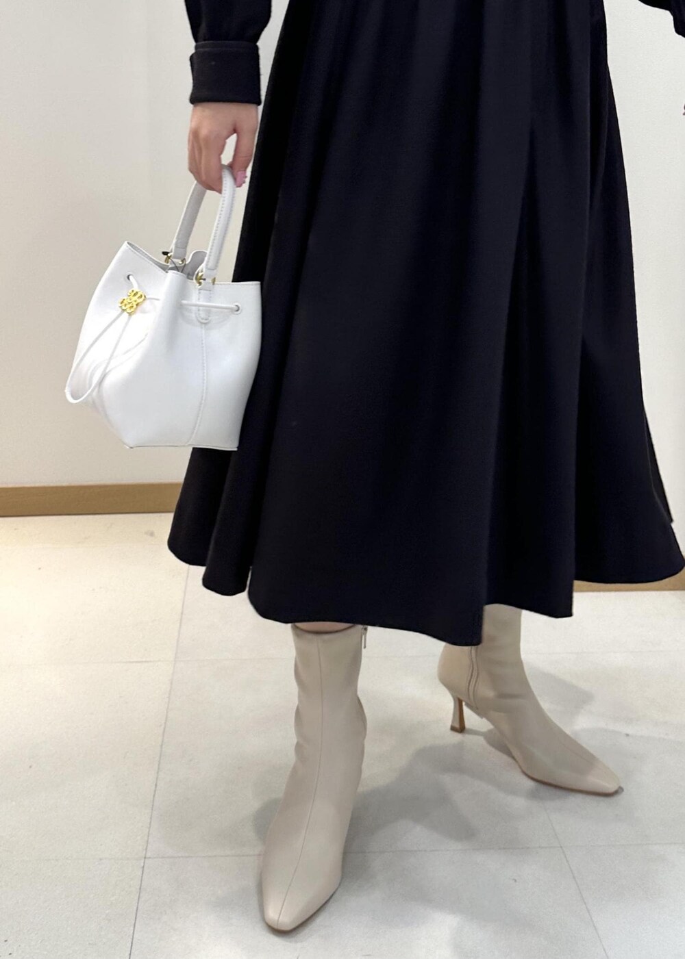 ホワイト系のブーツ、ホワイト系のハンドバッグ、ブルー系のワンピースを着用したレディースの冬コーディネートの6枚目の写真