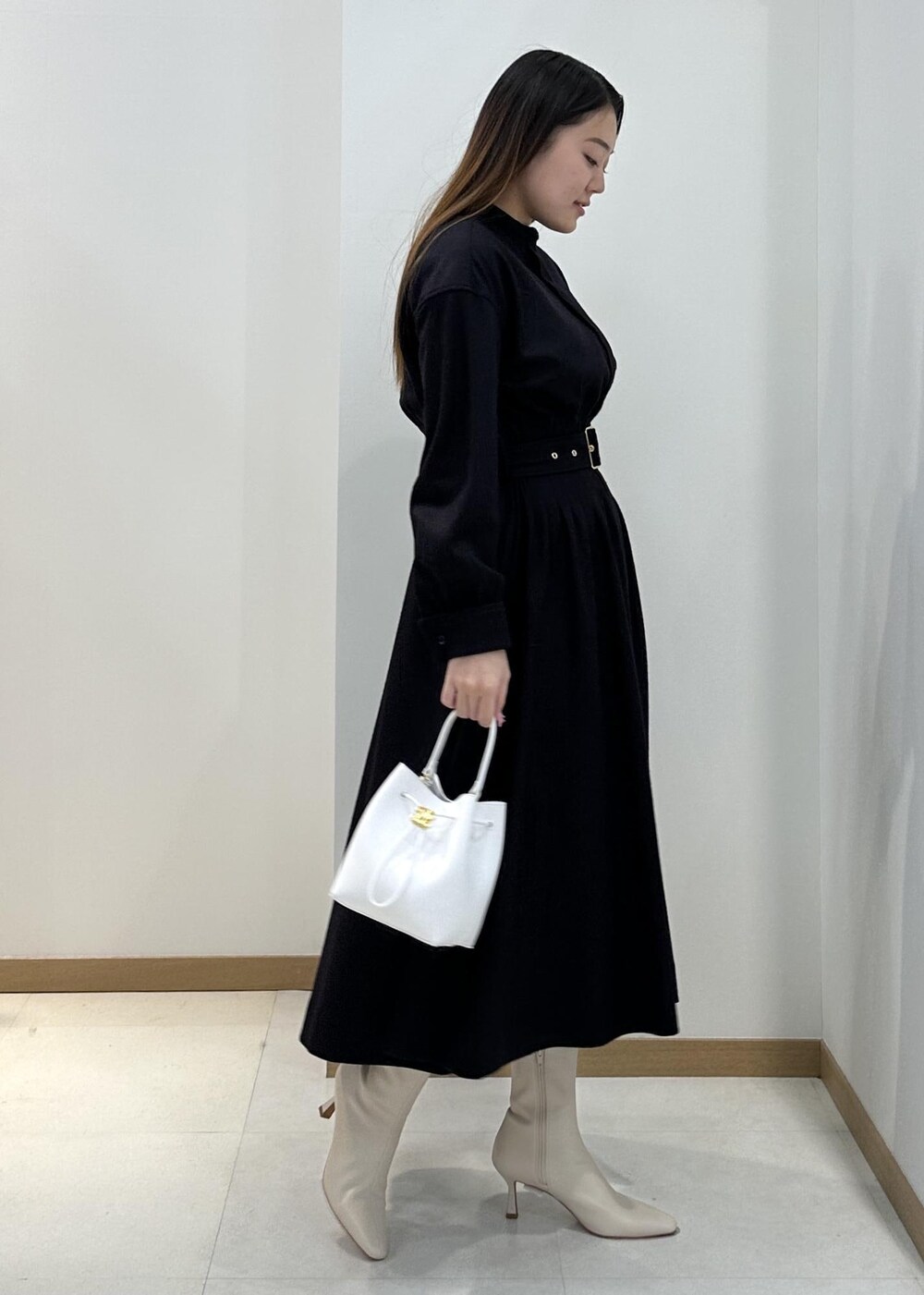 ホワイト系のブーツ、ホワイト系のハンドバッグ、ブルー系のワンピースを着用したレディースの冬コーディネートの2枚目の写真