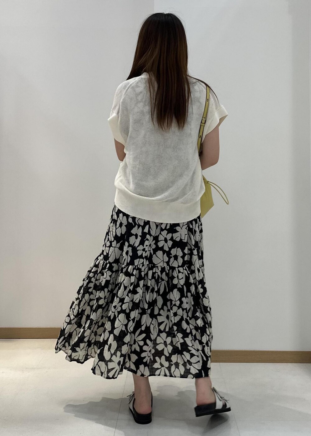 ベージュ系のハンドバッグ、ホワイト系のサンダル、ホワイト系のベストを着用したレディースの夏コーディネートの3枚目の写真