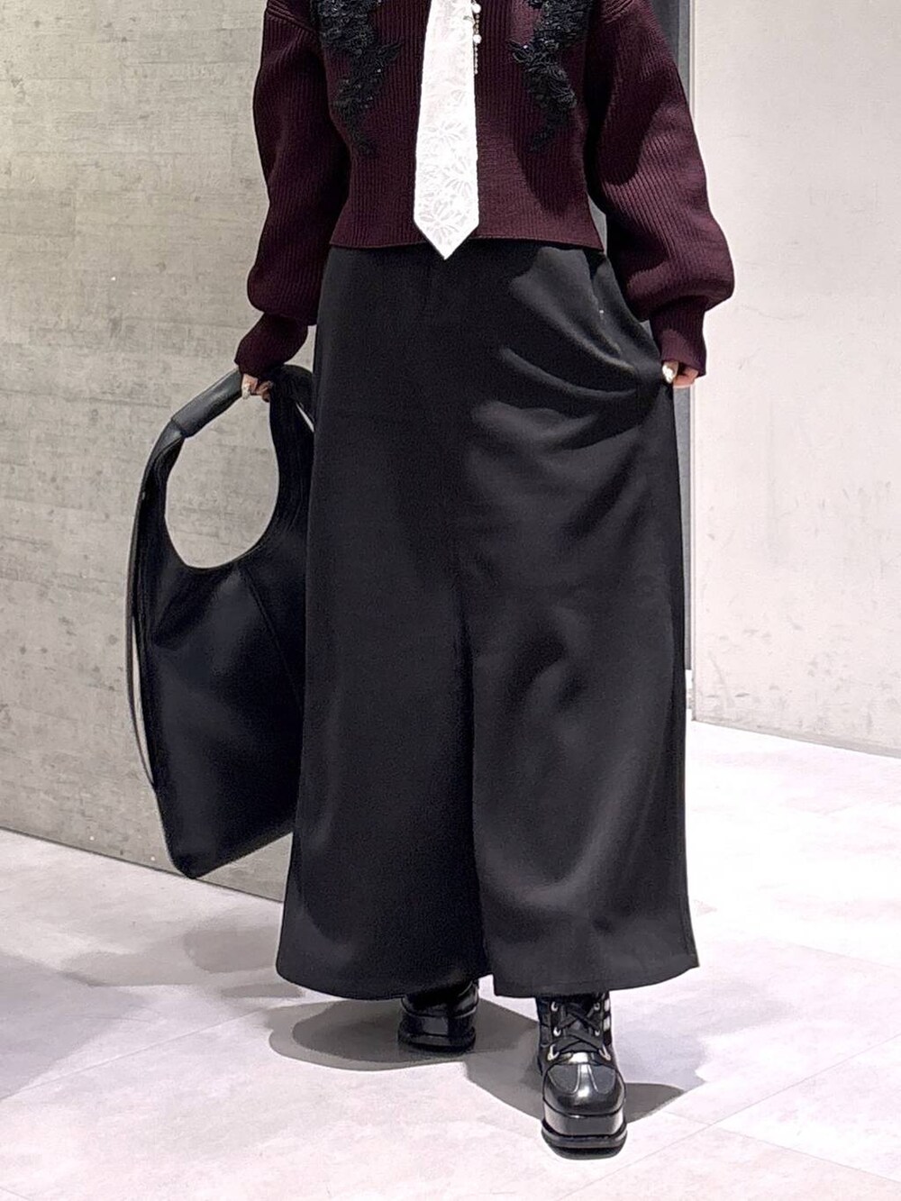 ブラック系のトートバッグ、ブラック系のブーツ、レッド系のニット/セーターを着用したレディースの秋コーディネートの3枚目の写真