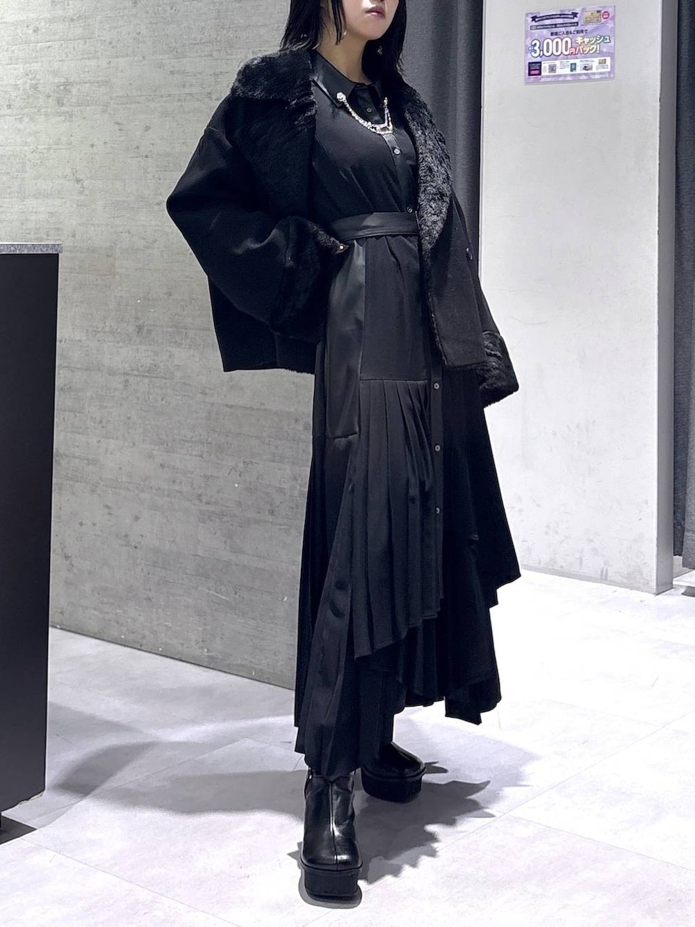 ブラック系のチェスターコート、ブラック系のブーツ、ブラック系のワンピースを着用したレディースの冬コーディネートの4枚目の写真