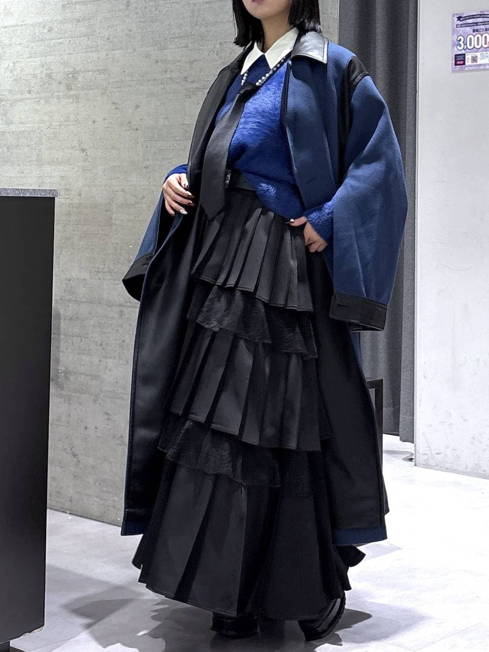 ブラック系のネクタイ、ブルー系のチェスターコート、ブルー系のニット/セーターを着用したレディースの冬コーディネートの9枚目の写真