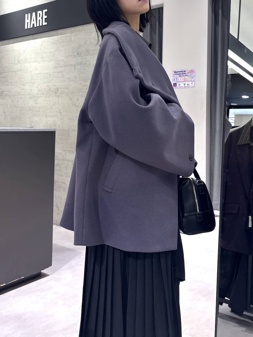 パープル系のチェスターコート、ブラック系のボストンバッグ、ブラック系のブーツを着用したレディースの冬コーディネートの8枚目の写真