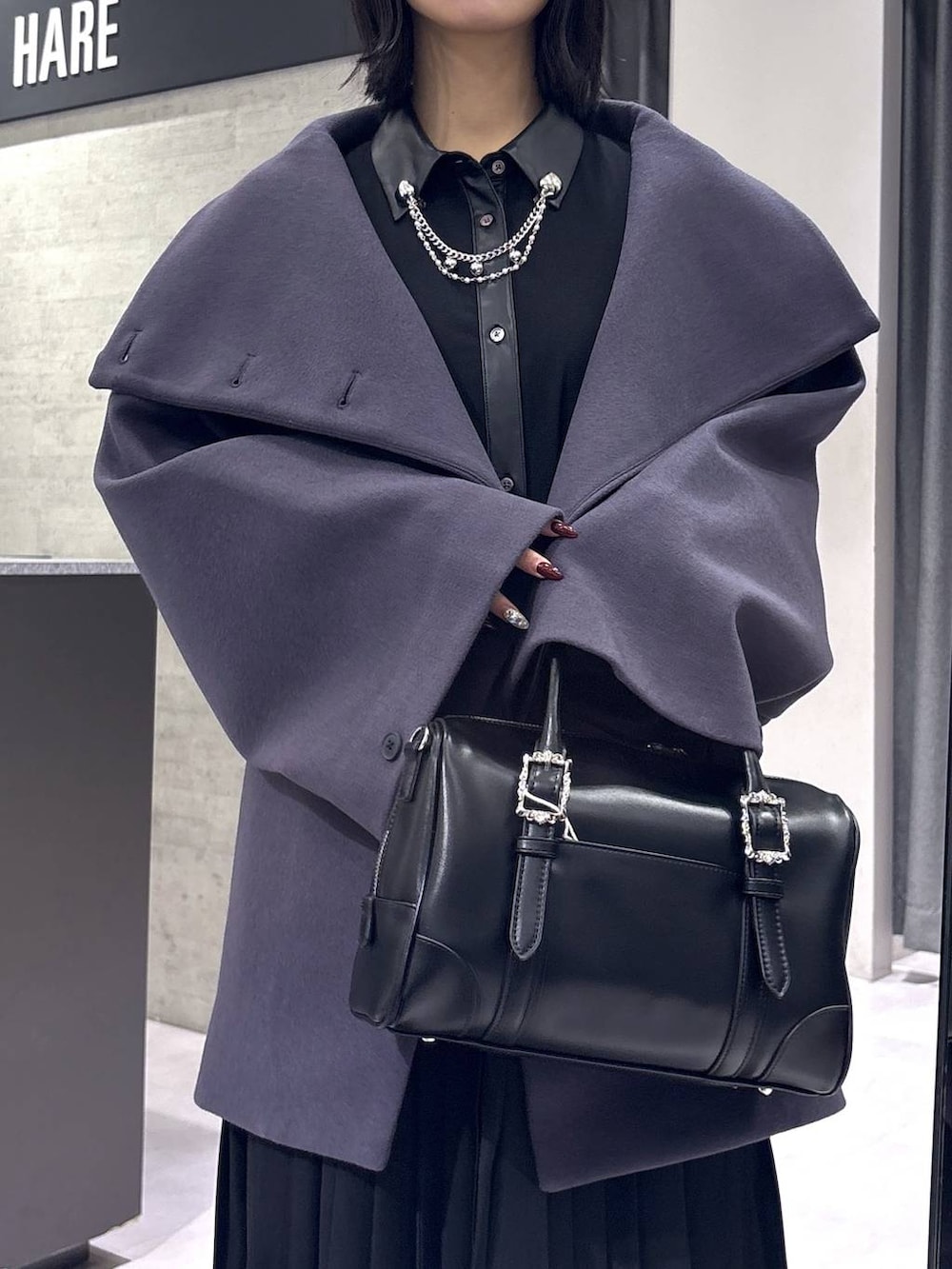 パープル系のチェスターコート、ブラック系のボストンバッグ、ブラック系のブーツを着用したレディースの冬コーディネートの2枚目の写真