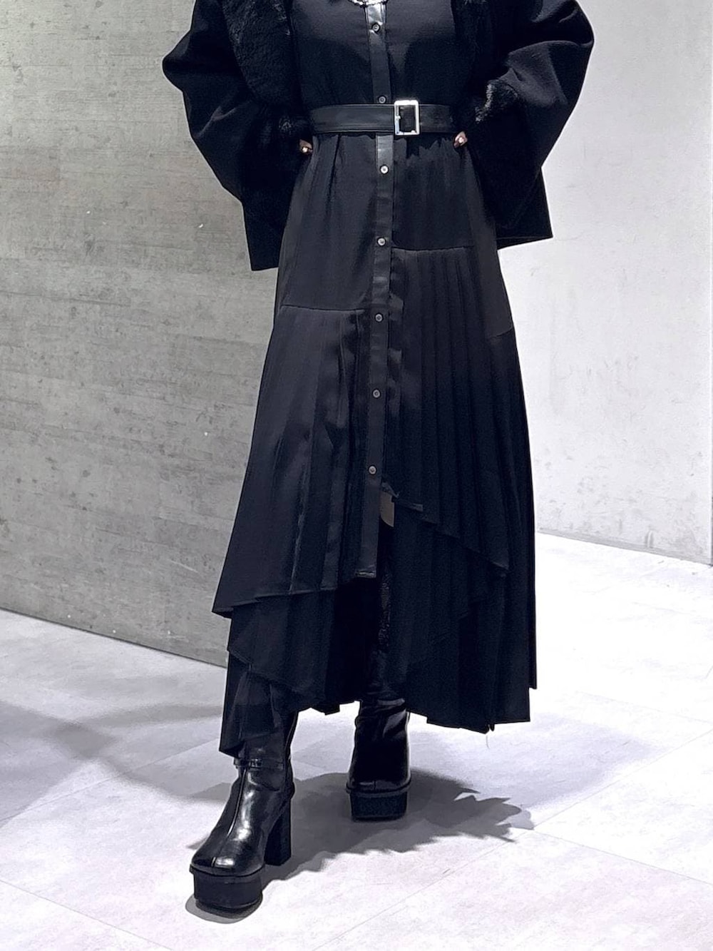 ブラック系のチェスターコート、ブラック系のブーツ、ブラック系のワンピースを着用したレディースの冬コーディネートの3枚目の写真