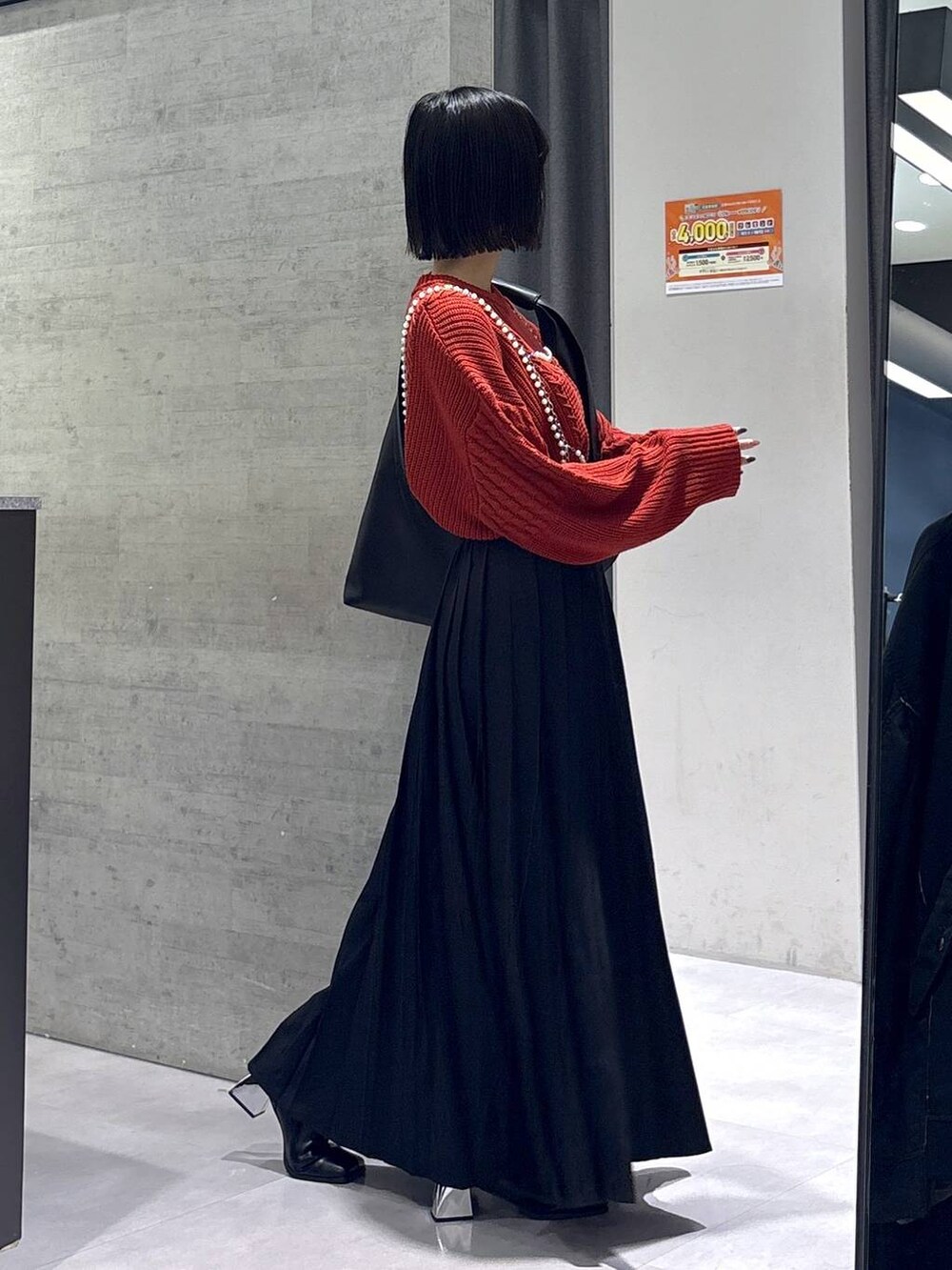 ブラック系のタンクトップ、ブラック系のトートバッグ、ブラック系のブーツを着用したレディースの秋コーディネートの6枚目の写真