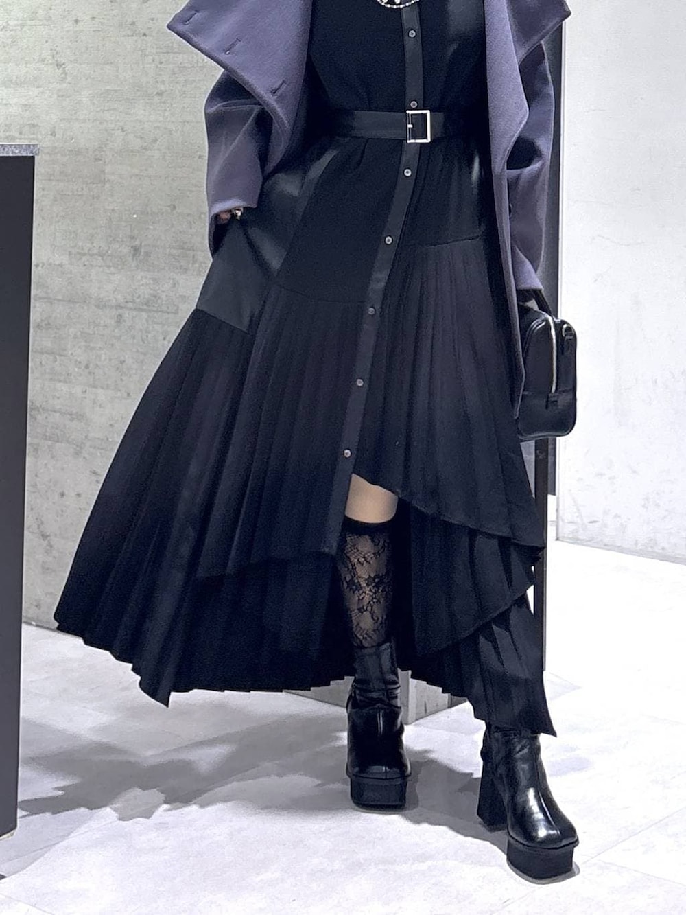 パープル系のチェスターコート、ブラック系のボストンバッグ、ブラック系のブーツを着用したレディースの冬コーディネートの3枚目の写真