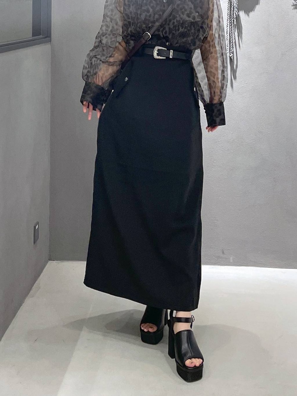 ブラック系のタンクトップ、ブラック系のサンダル、ブラウン系のショルダーバッグを着用したレディースの夏コーディネートの3枚目の写真