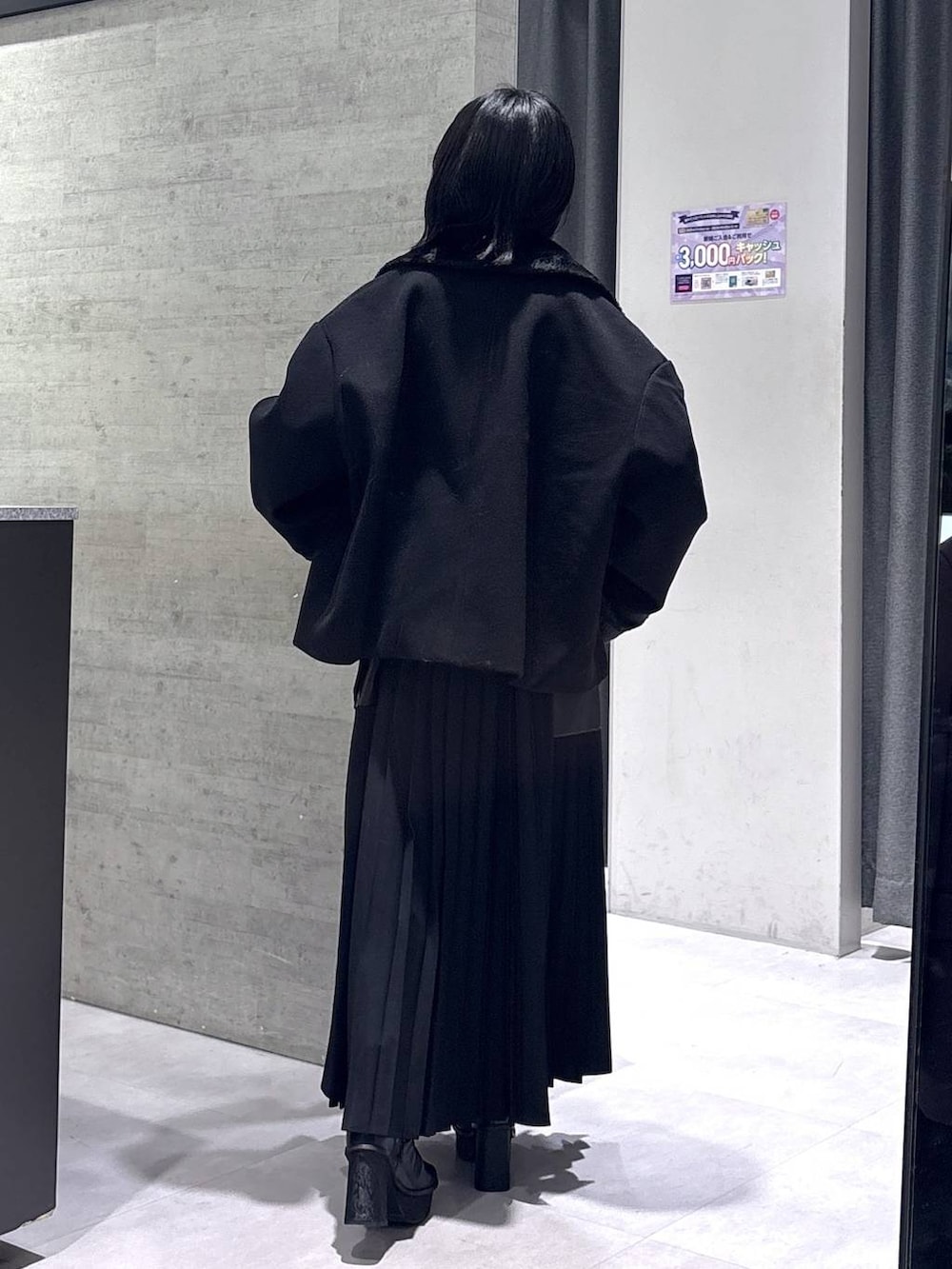 ブラック系のチェスターコート、ブラック系のブーツ、ブラック系のワンピースを着用したレディースの冬コーディネートの7枚目の写真