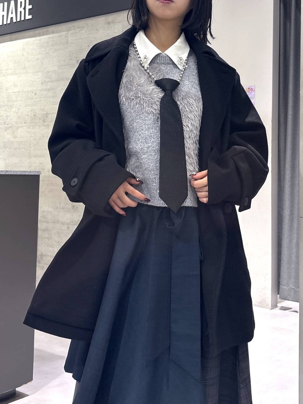 ブラック系のネクタイ、ブラック系のトレンチコート、グリーン系のブーツを着用したレディースの秋コーディネートの2枚目の写真