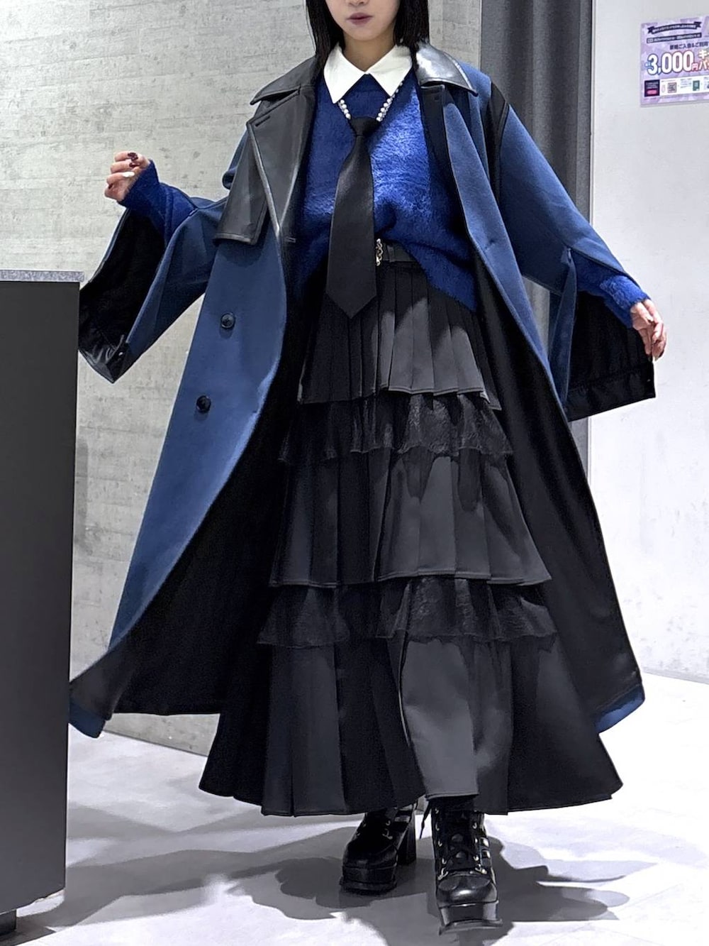 ブラック系のネクタイ、ブルー系のチェスターコート、ブルー系のニット/セーターを着用したレディースの冬コーディネートの4枚目の写真