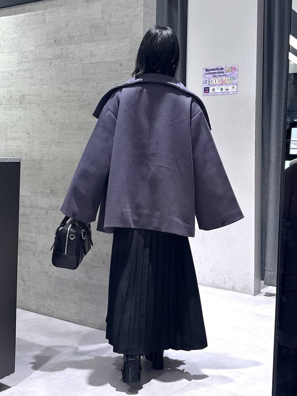 パープル系のチェスターコート、ブラック系のボストンバッグ、ブラック系のブーツを着用したレディースの冬コーディネートの7枚目の写真