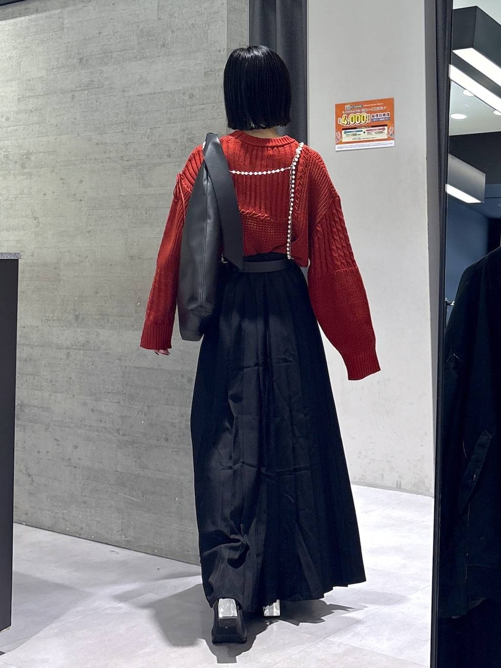 ブラック系のタンクトップ、ブラック系のトートバッグ、ブラック系のブーツを着用したレディースの秋コーディネートの7枚目の写真