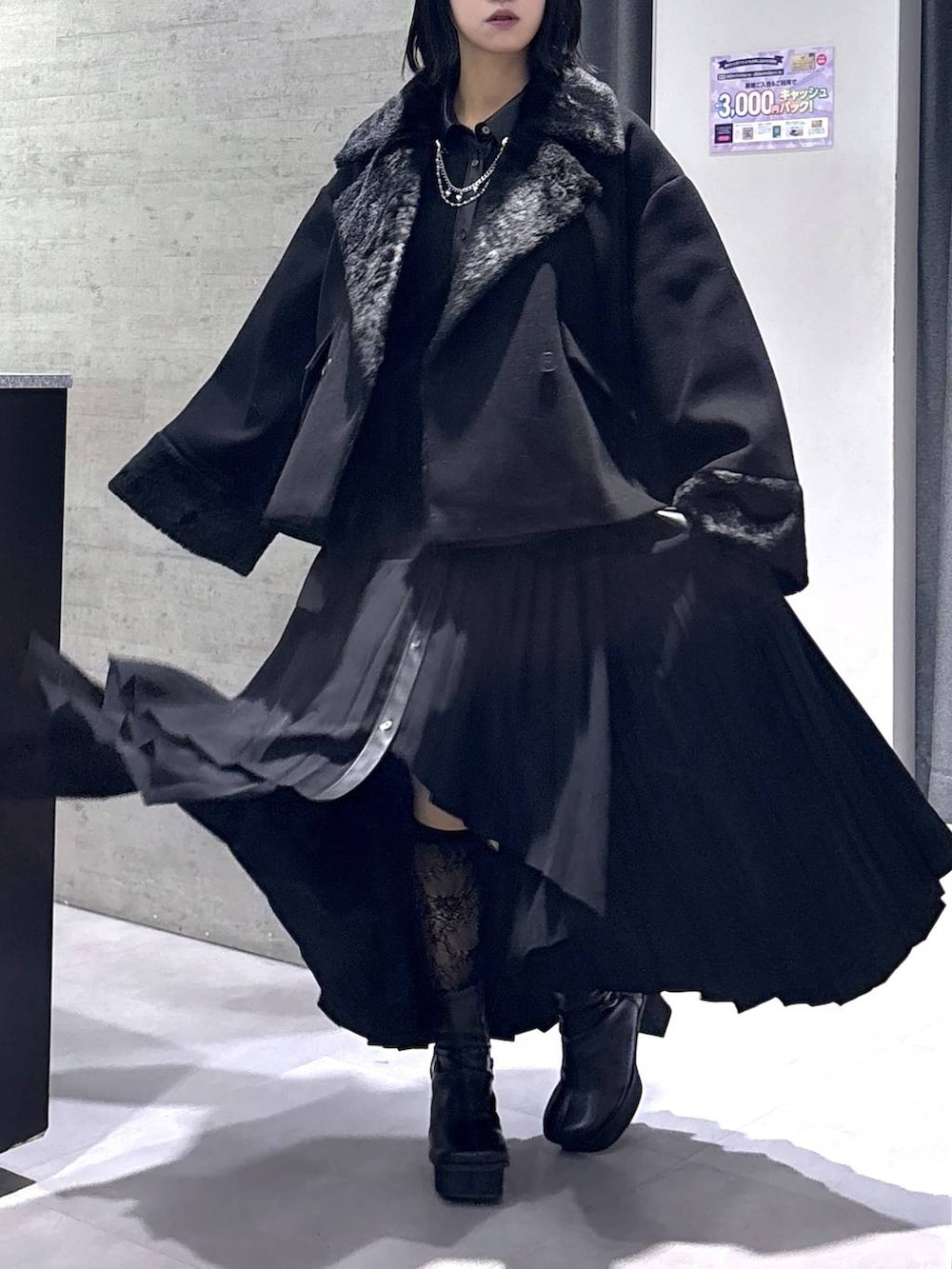 ブラック系のチェスターコート、ブラック系のブーツ、ブラック系のワンピースを着用したレディースの冬コーディネートの9枚目の写真