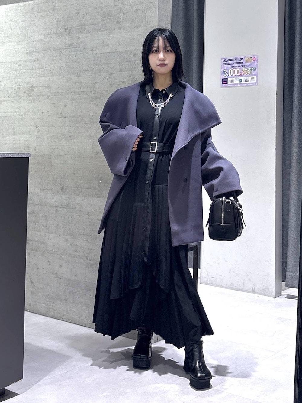 パープル系のチェスターコート、ブラック系のボストンバッグ、ブラック系のブーツを着用したレディースの冬コーディネートの5枚目の写真