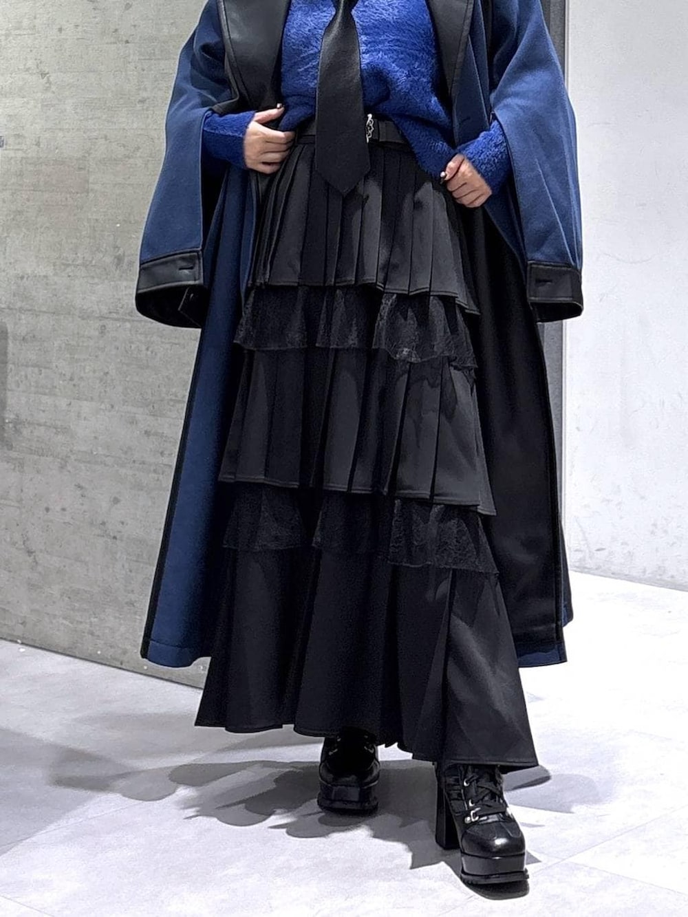 ブラック系のネクタイ、ブルー系のチェスターコート、ブルー系のニット/セーターを着用したレディースの冬コーディネートの3枚目の写真