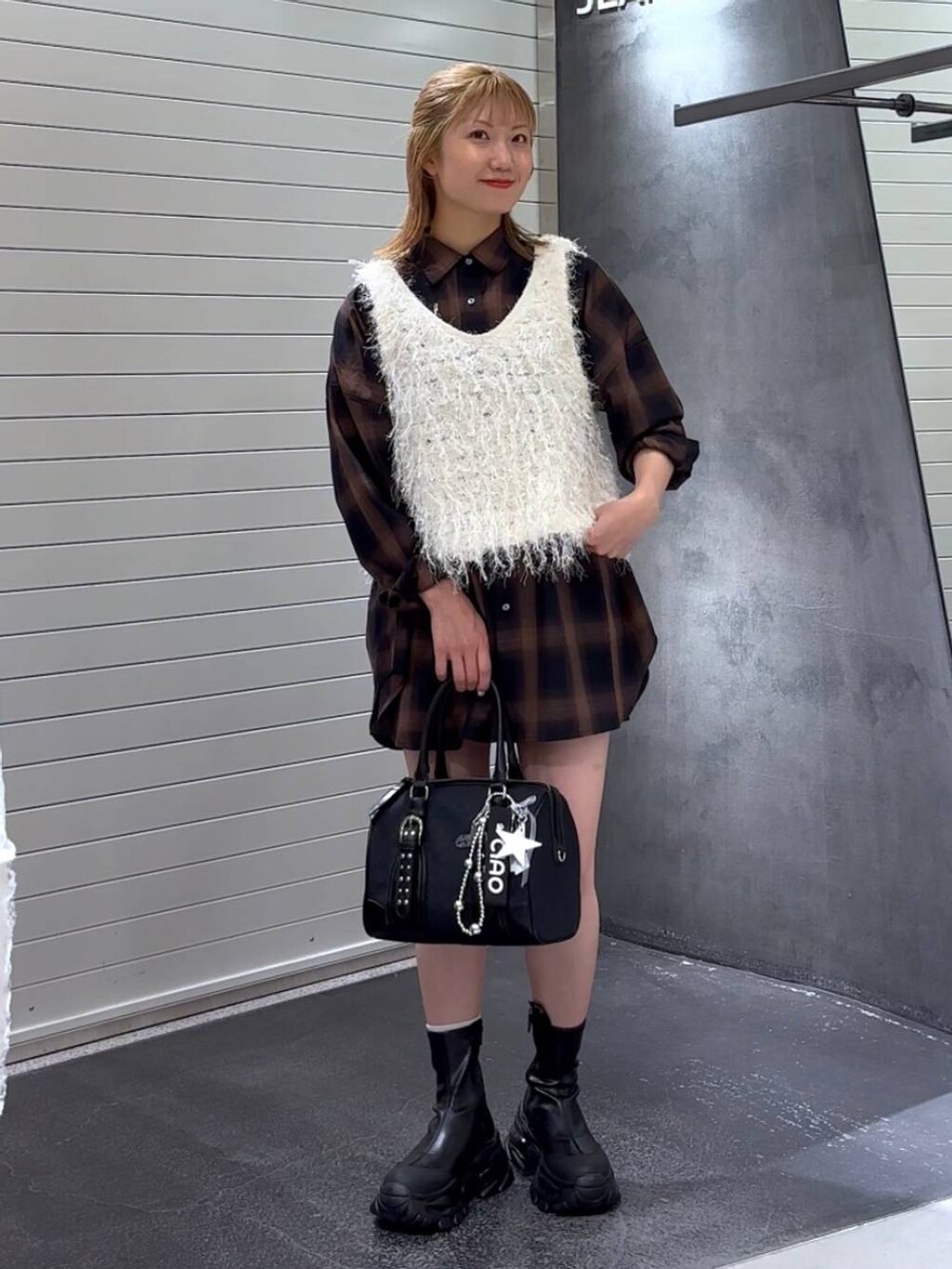 ブラウン系のシャツ/ブラウス、ブラック系のブーツ、ブラック系のボストンバッグを着用したレディースの秋コーディネートの2枚目の写真