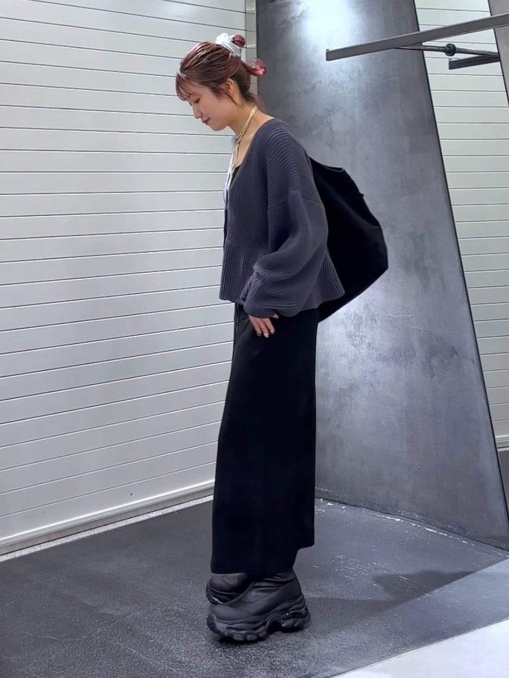 ブラック系のスカート、ブラック系のブーツ、ブラック系のトートバッグを着用したレディースの秋コーディネートの6枚目の写真