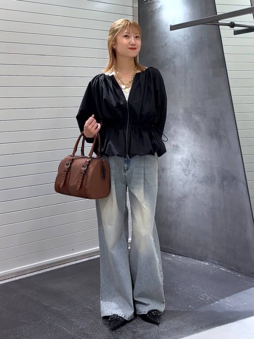 ブルー系のデニムパンツ、ブラック系のパンプス、レッド系のボストンバッグを着用したレディースの秋コーディネートの2枚目の写真