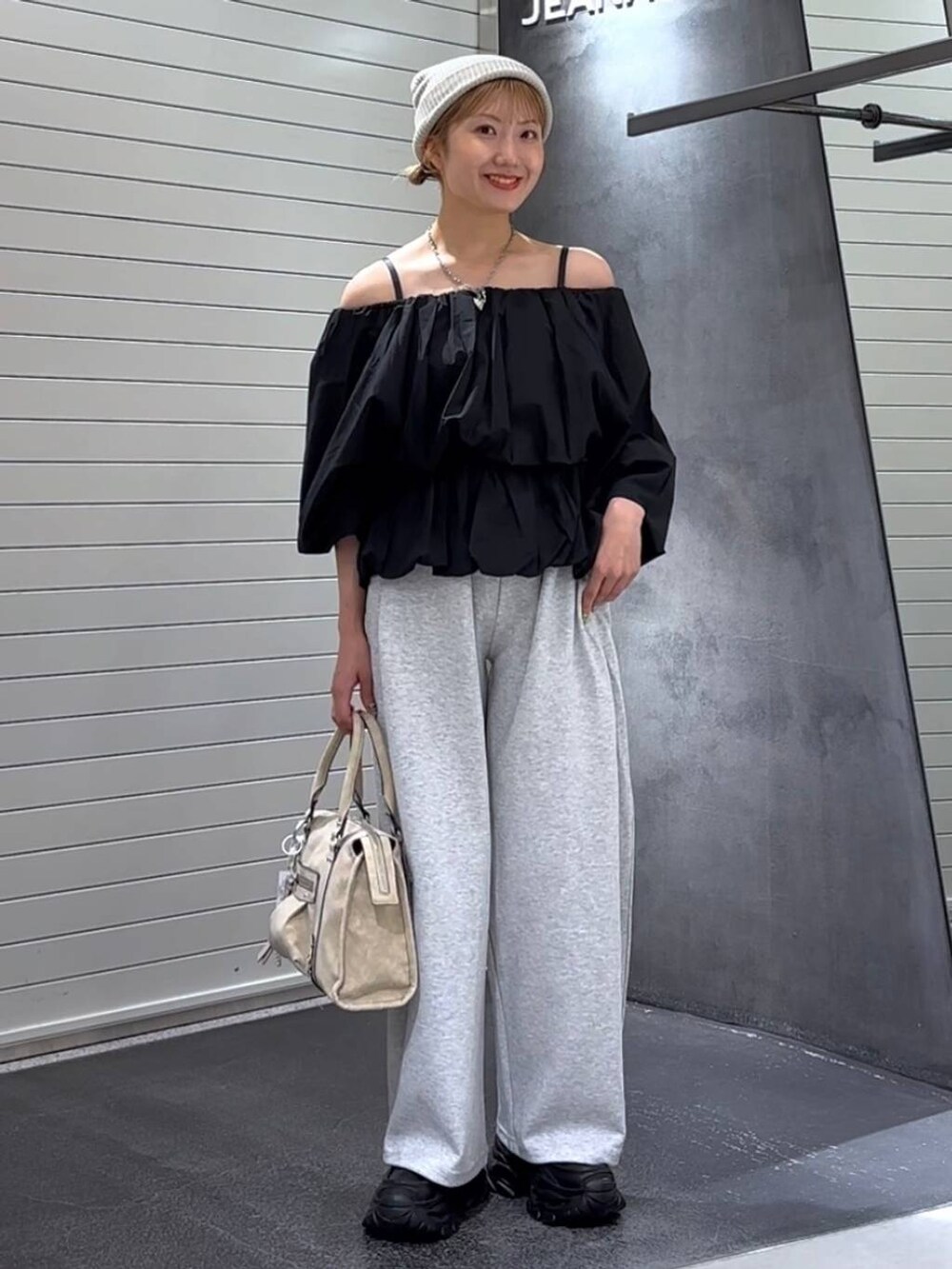 ベージュ系のボストンバッグ、ブラック系のローファー、グレー系のスウェットパンツを着用したレディースの秋コーディネートの2枚目の写真