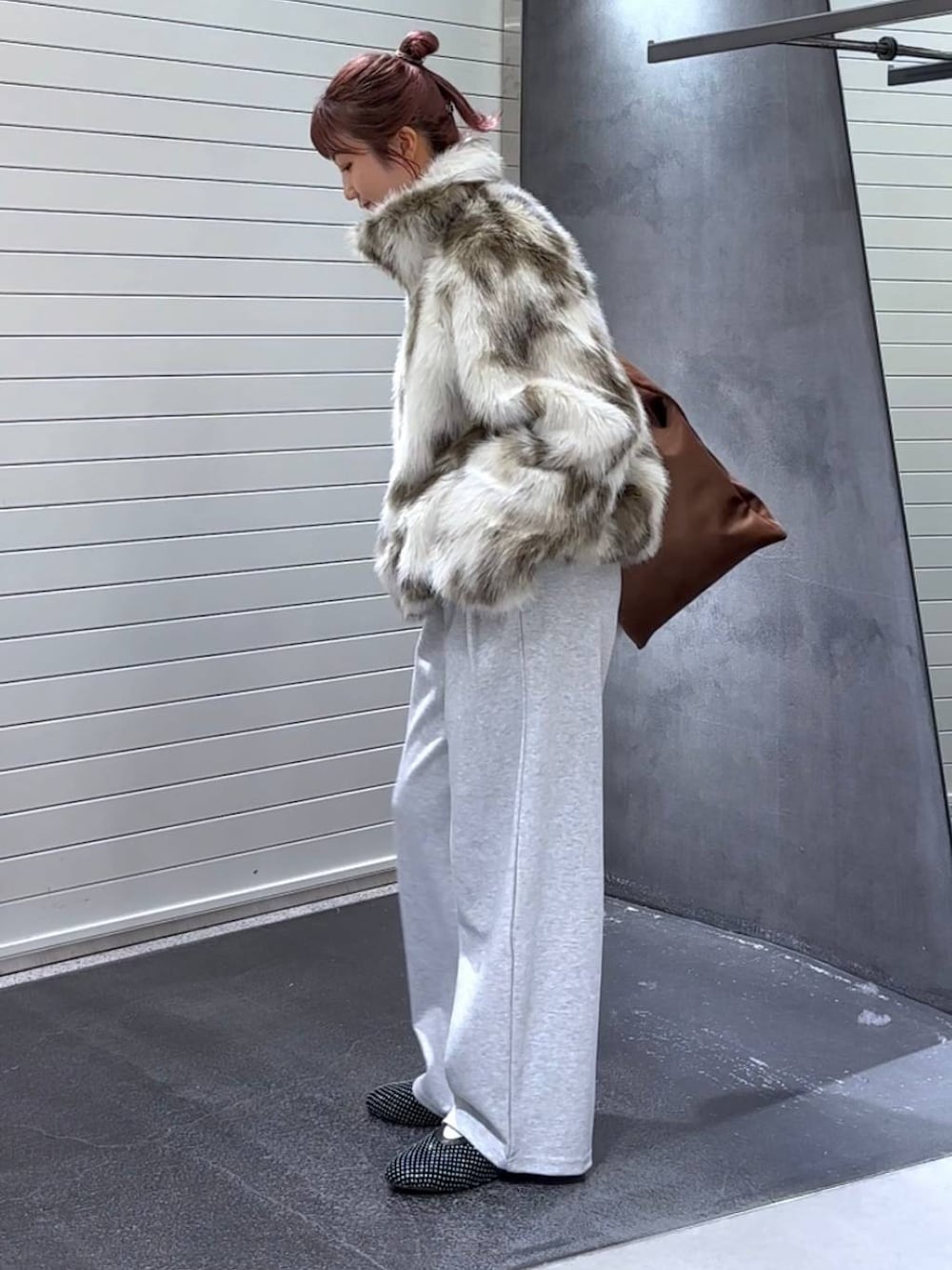 グレー系のブルゾン、ブラウン系のトートバッグ、グレー系のスウェットパンツを着用したレディースの秋コーディネートの6枚目の写真