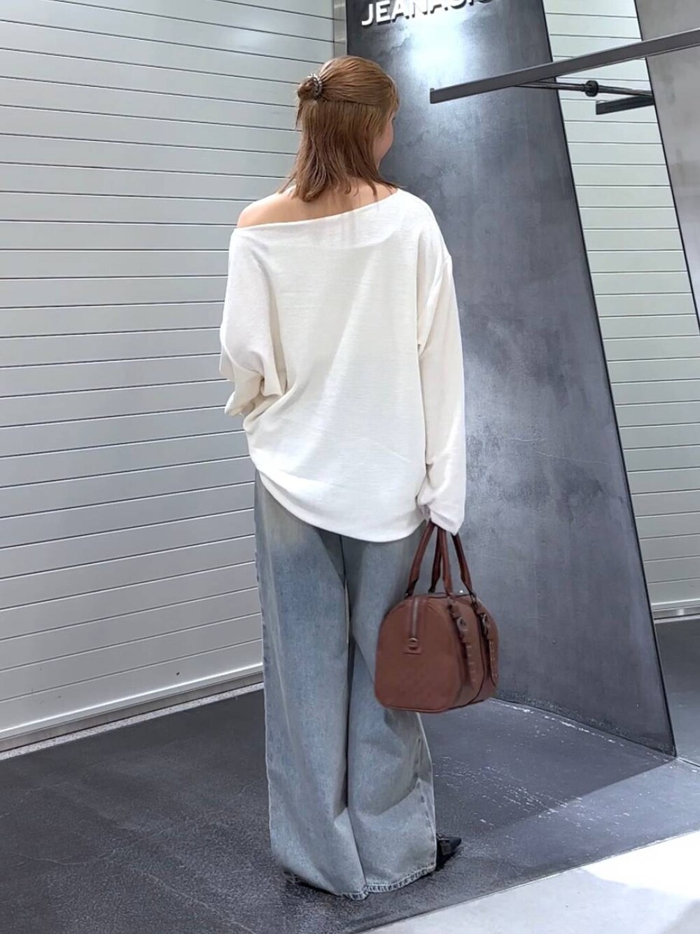 ブルー系のデニムパンツ、ブラック系のパンプス、レッド系のボストンバッグを着用したレディースの秋コーディネートの5枚目の写真