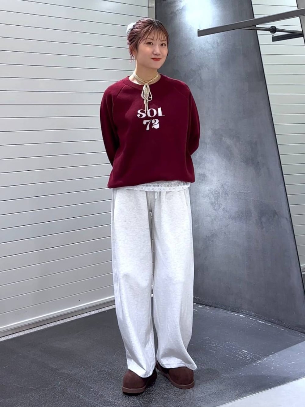 ブラウン系のその他シューズ、レッド系のニット/セーター、ベージュ系のスウェットパンツを着用したレディースの秋コーディネートの2枚目の写真