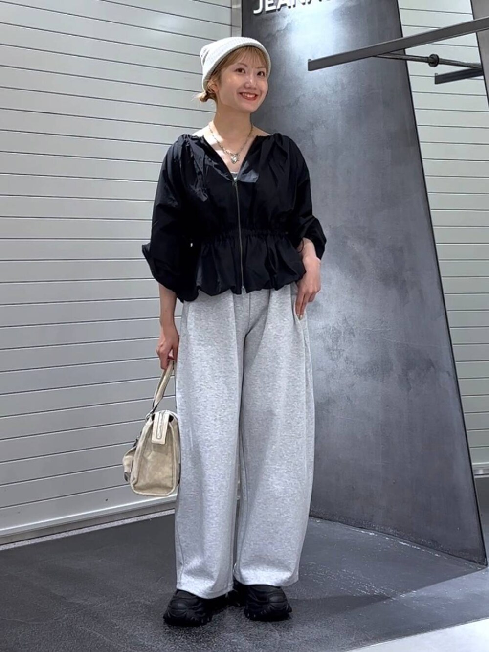 ベージュ系のボストンバッグ、グレー系のスウェットパンツ、ブラック系のローファーを着用したレディースの秋コーディネートの3枚目の写真