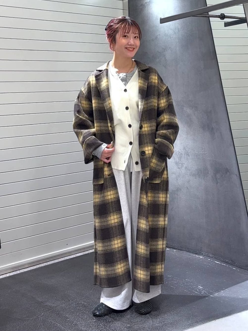 ブラウン系のチェスターコート、ブラック系のパンプス、グレー系のTシャツ/カットソーを着用したレディースの冬コーディネートの3枚目の写真