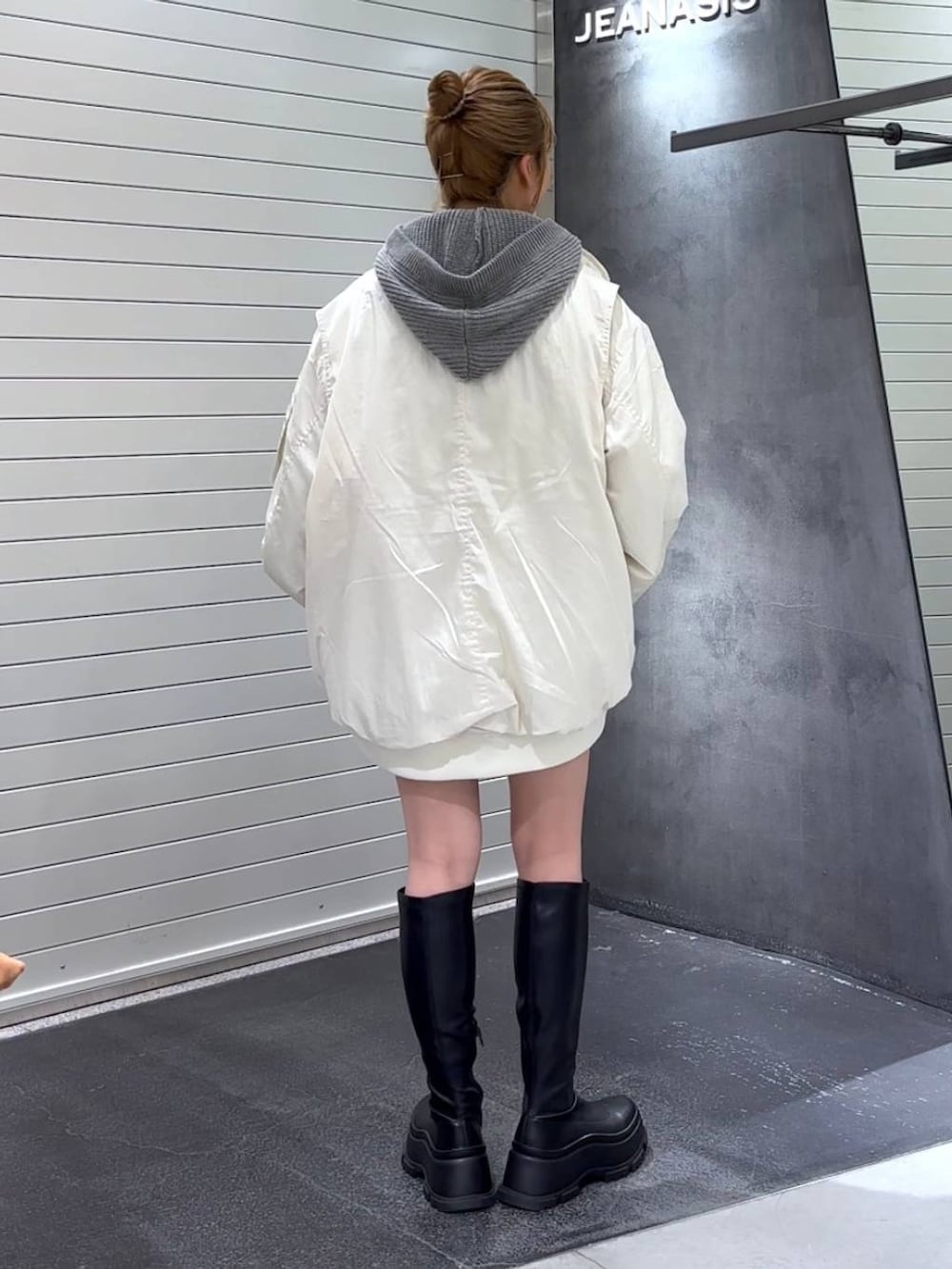 ホワイト系のブルゾン、ブラック系のブーツ、ホワイト系のタンクトップを着用したレディースの秋コーディネートの5枚目の写真