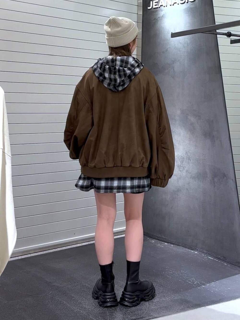 ホワイト系のTシャツ/カットソー、ブラウン系のブルゾン、ブラック系のブーツを着用したレディースの秋コーディネートの5枚目の写真