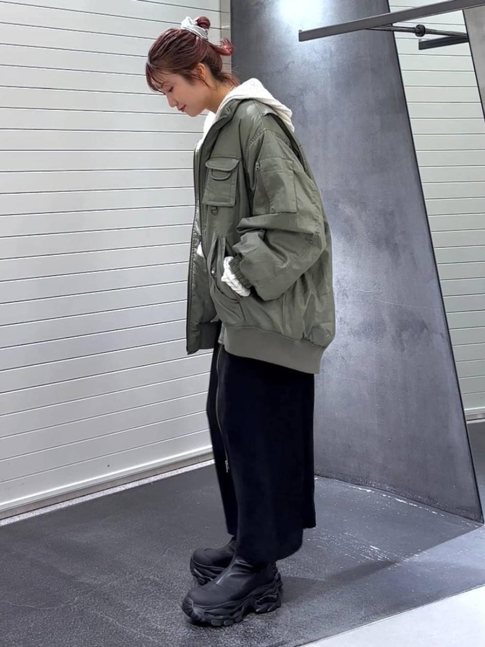 ブラック系のスカート、ブラック系のブーツ、グリーン系のブルゾンを着用したレディースの秋コーディネートの6枚目の写真