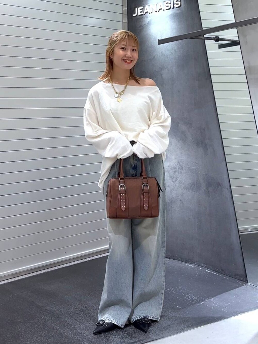 ブルー系のデニムパンツ、ブラック系のパンプス、レッド系のボストンバッグを着用したレディースの秋コーディネートの2枚目の写真