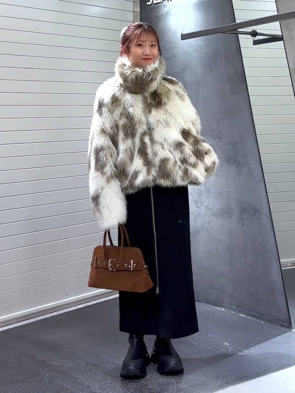 ブラック系のスカート、ホワイト系のブルゾン、ブラック系のブーツを着用したレディースの秋コーディネートの2枚目の写真