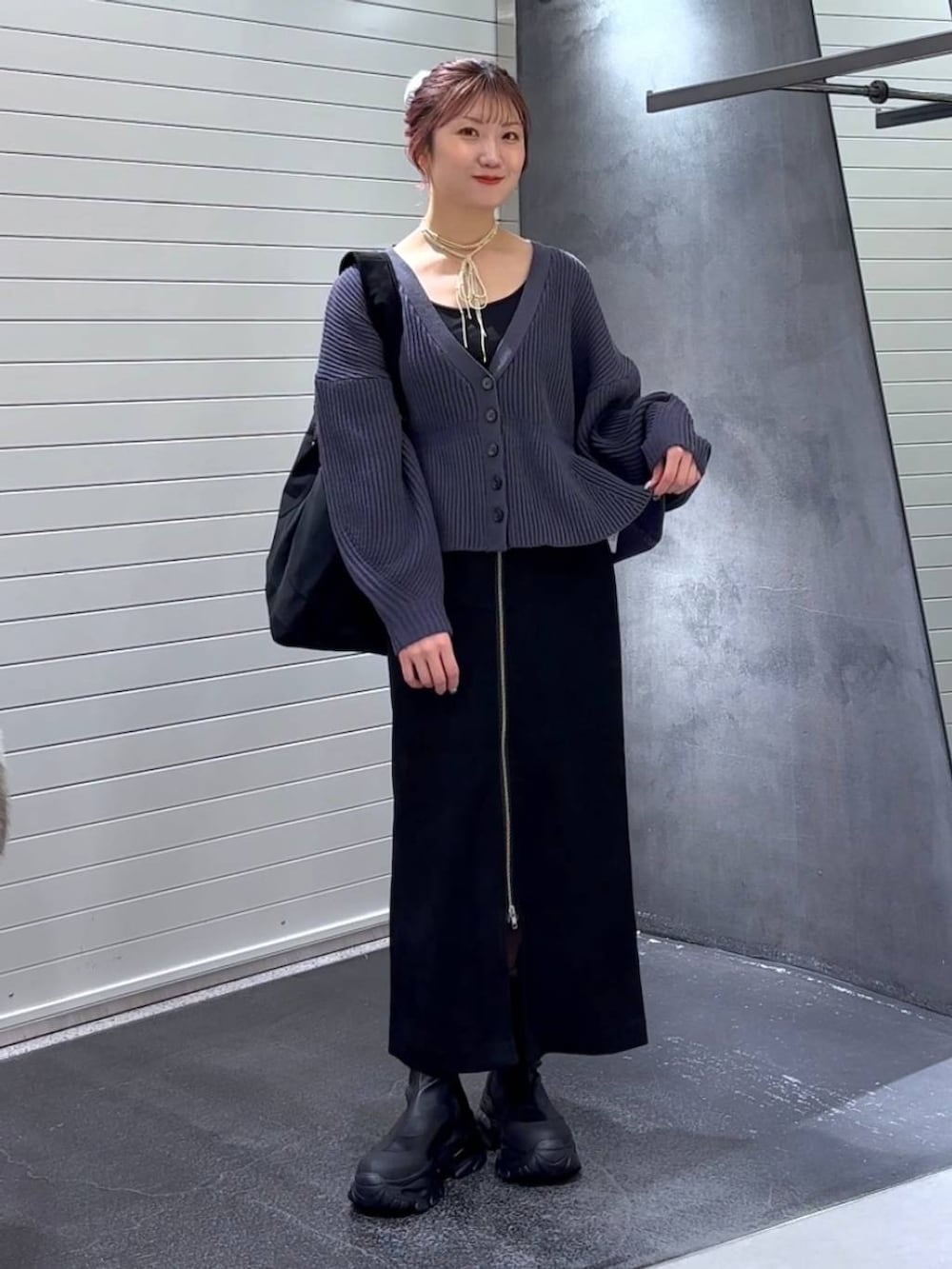 ブラック系のスカート、ブラック系のブーツ、ブラック系のトートバッグを着用したレディースの秋コーディネートの3枚目の写真