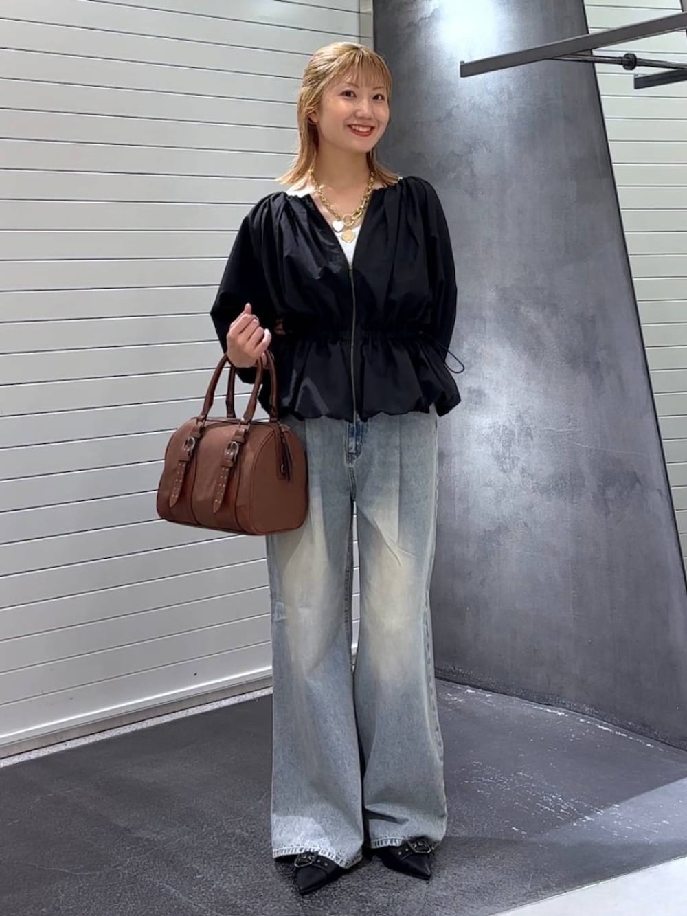 ブルー系のデニムパンツ、ブラック系のパンプス、レッド系のボストンバッグを着用したレディースの秋コーディネートの3枚目の写真