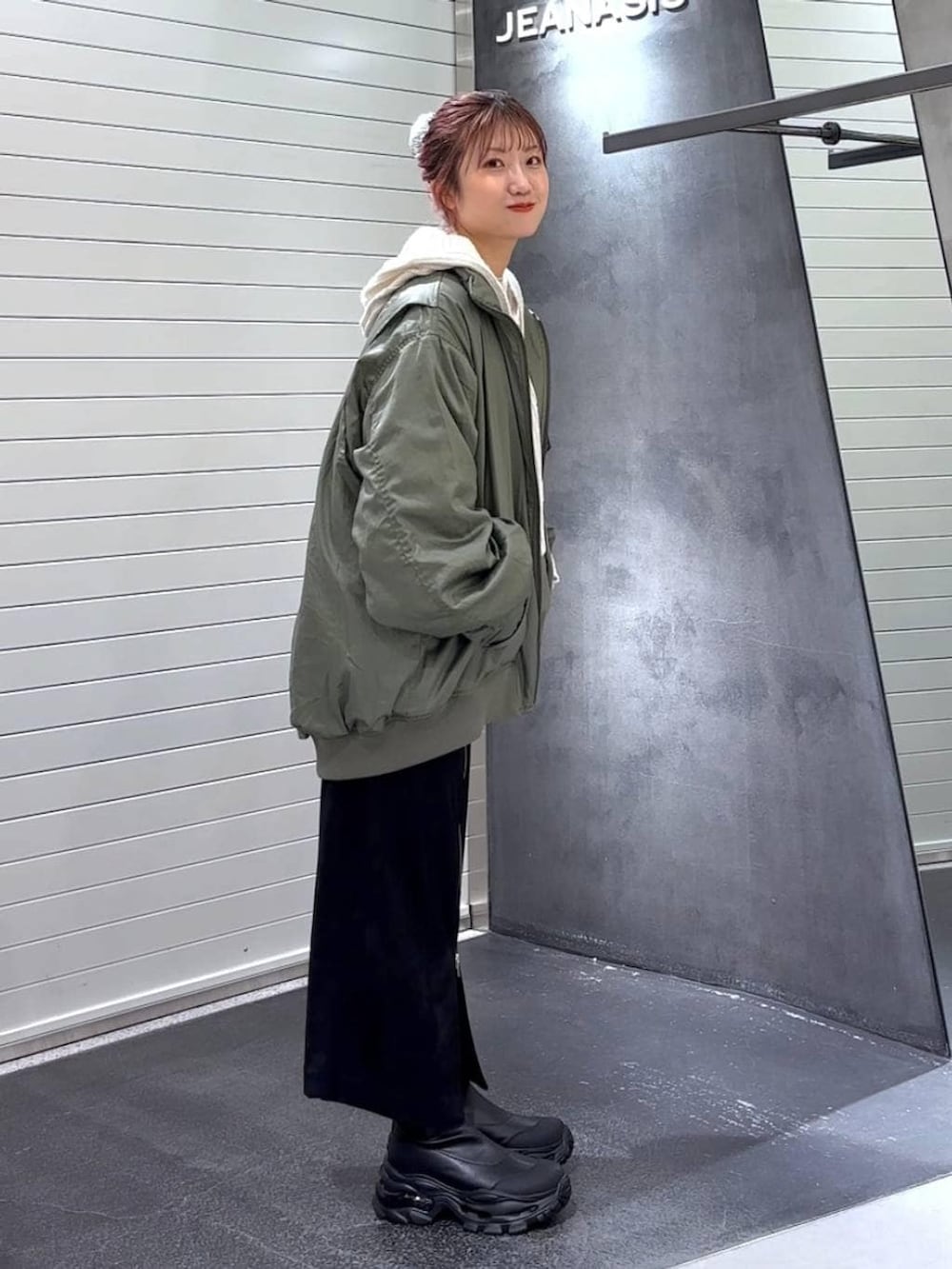 ブラック系のスカート、ブラック系のブーツ、グリーン系のブルゾンを着用したレディースの秋コーディネートの3枚目の写真