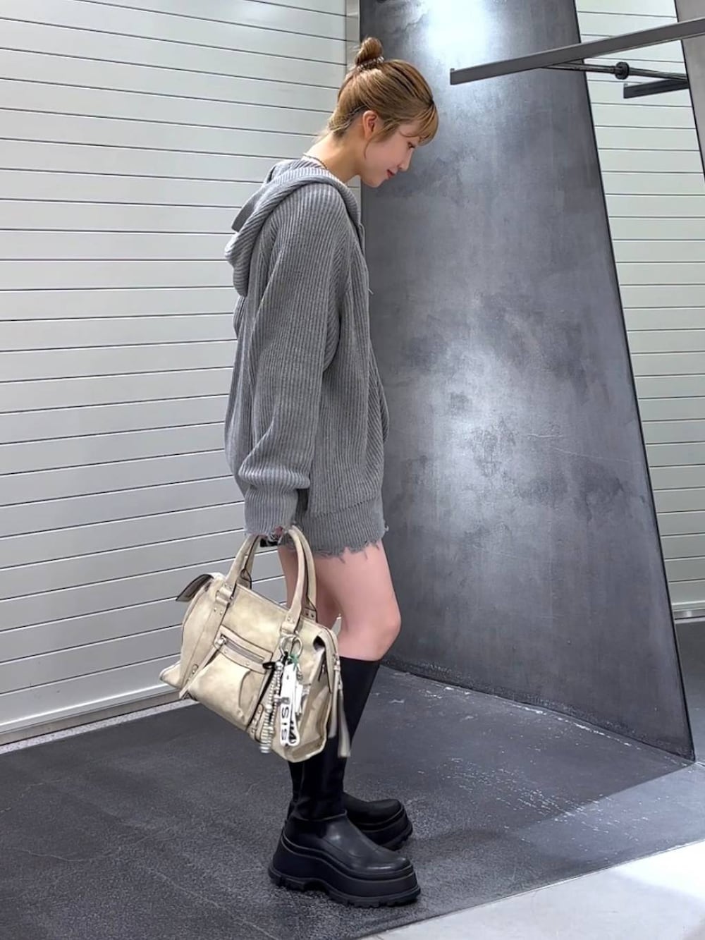 ベージュ系のボストンバッグ、ブラック系のブーツ、ホワイト系のタンクトップを着用したレディースの秋コーディネートの3枚目の写真