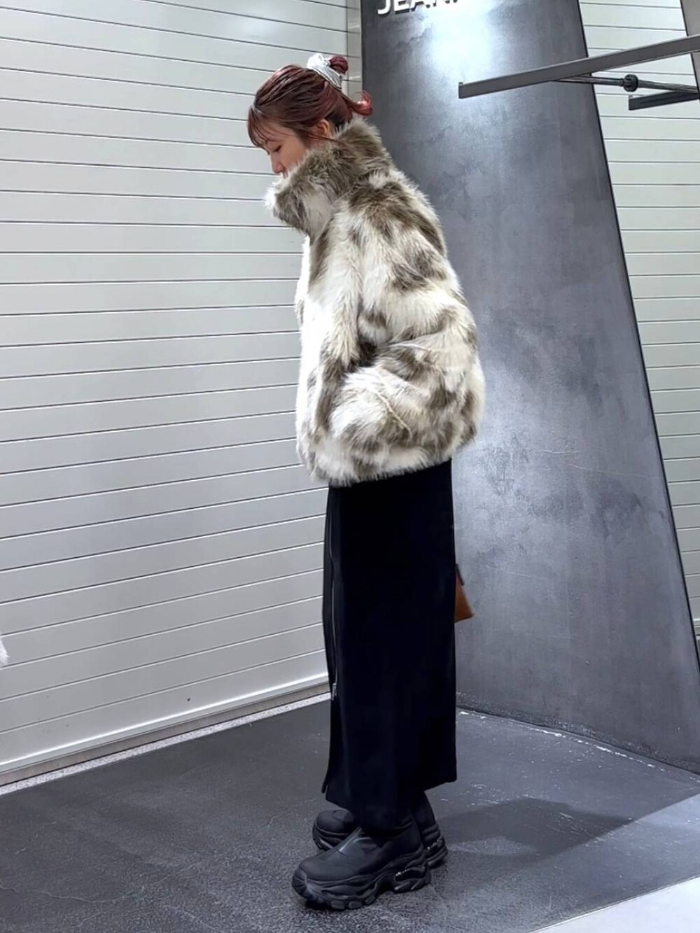 ブラック系のスカート、ホワイト系のブルゾン、ブラック系のブーツを着用したレディースの秋コーディネートの6枚目の写真